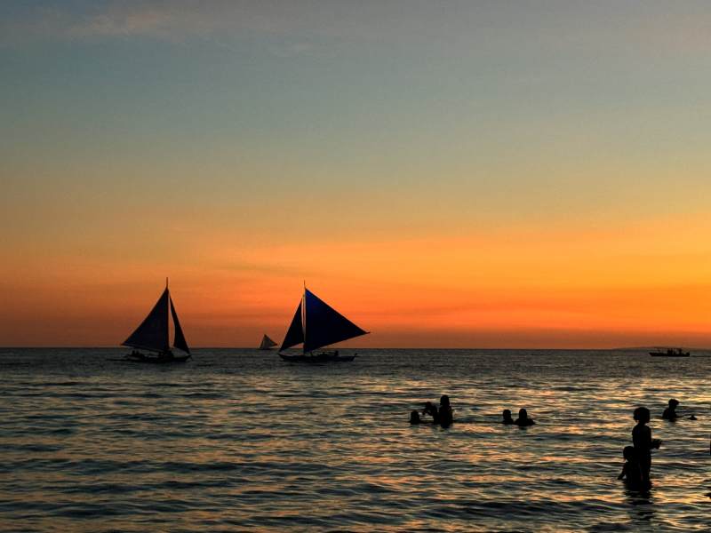夕阳帆船 海中嬉戏人影图片