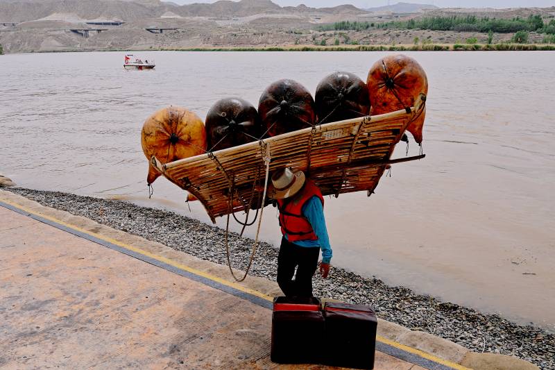 宁夏沙坡头黄河漂流船工扛着羊皮筏上岸图片