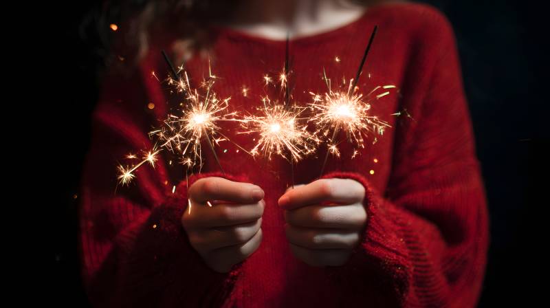 红毛衣握 sparklers 温暖夜图片