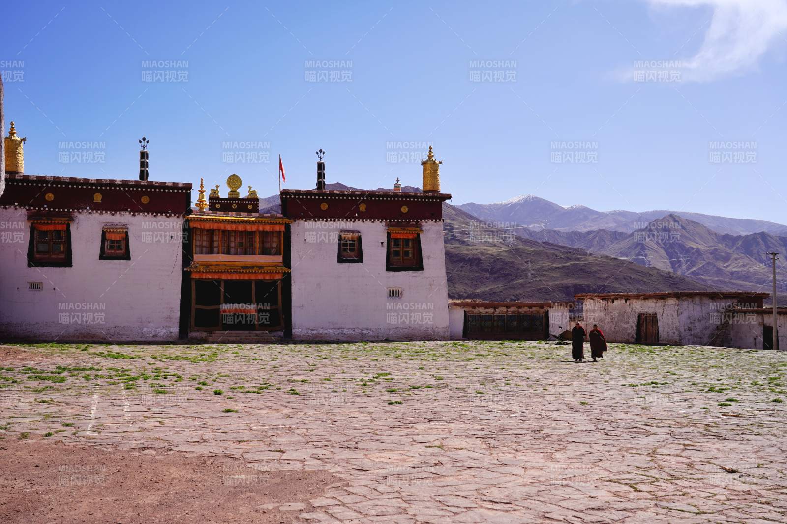 藏式白墙金顶寺 远山映衬僧人行图片