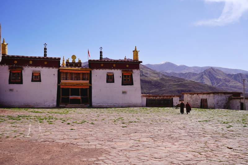 藏式白墙金顶寺 远山映衬僧人行图片