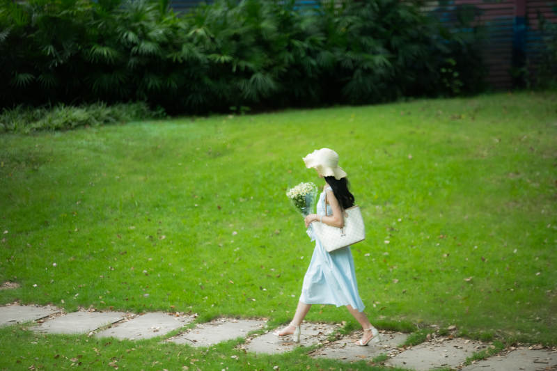 绿茵小径 白帽少女持花行图片