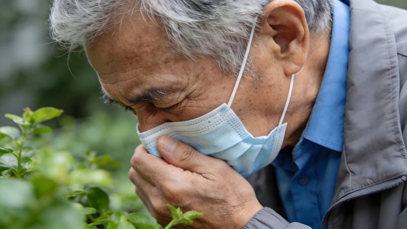 老人戴口罩闻花香图片