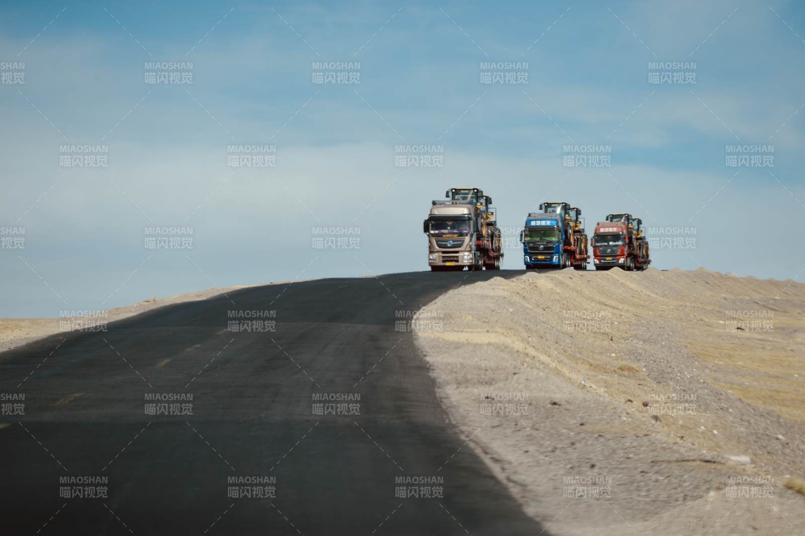 三辆卡车行驶在荒漠公路上图片