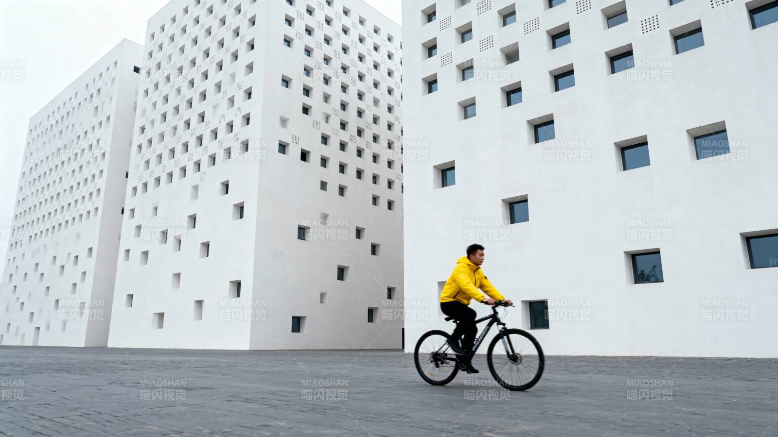 黄衣骑行者穿梭白楼间图片