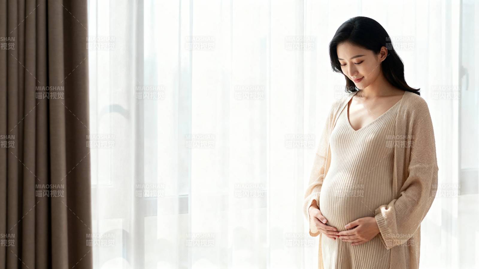 孕妇窗边轻抚孕肚微笑图片