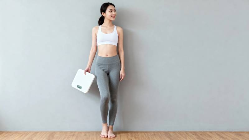 健身女孩持体重秤微笑站立图片