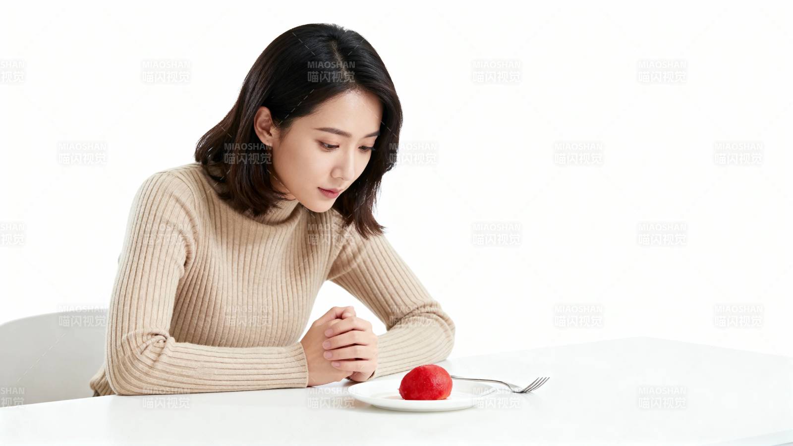 女子凝视盘中红苹果图片