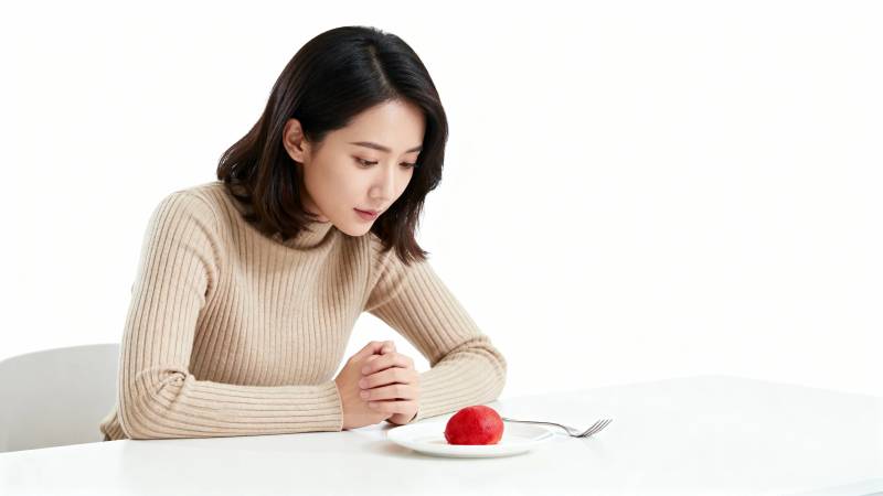 女子凝视盘中红苹果图片