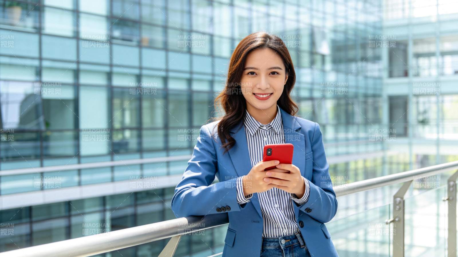 职场女性持红手机微笑图片