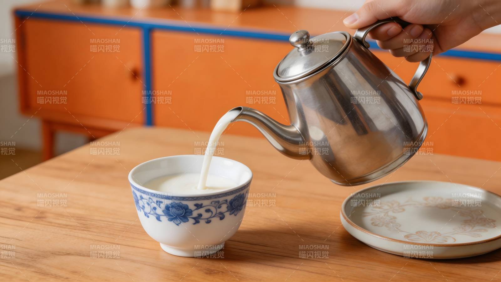 银壶斟奶入青花碗图片
