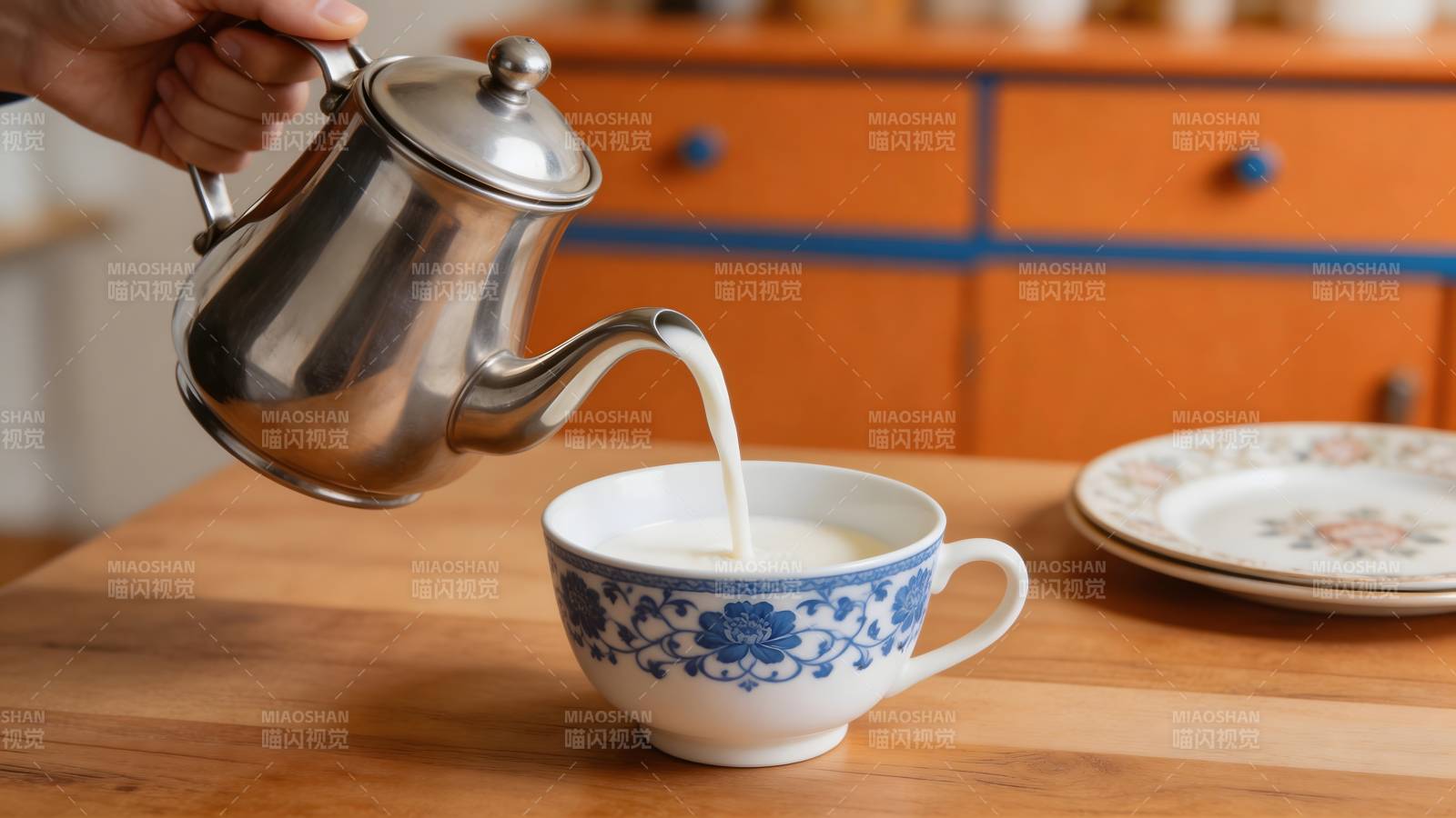 银壶倒奶入蓝花瓷杯图片
